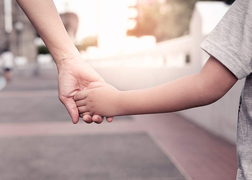 Child Custody During Deployment - A parent holds the hand of a small boy in the sunset